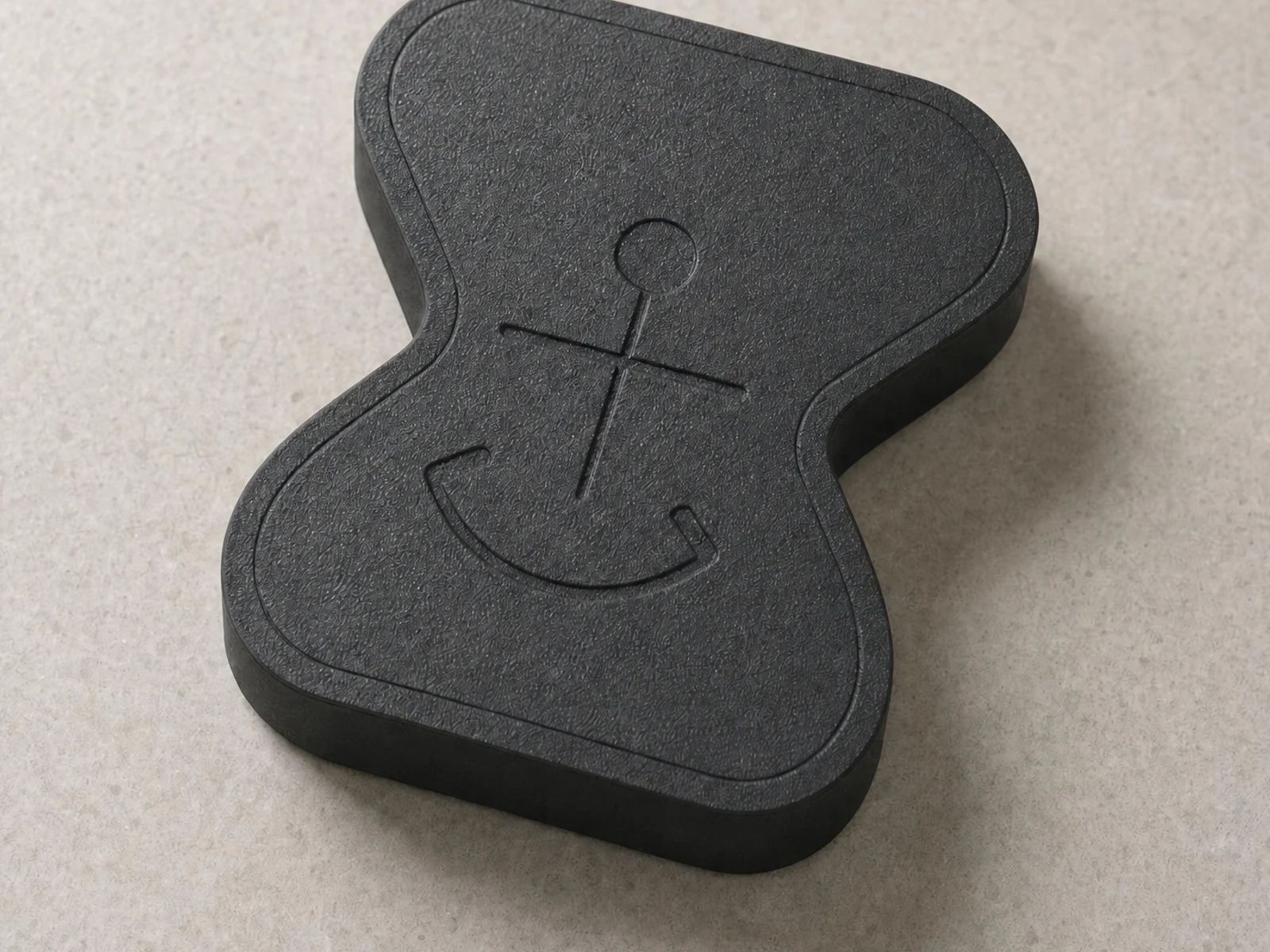 Close detail of Anchor's matte-charcoal printed texture and shallow debossing